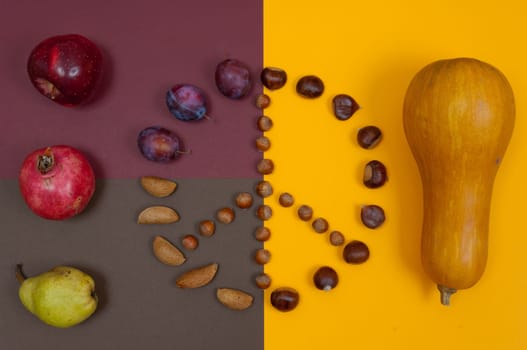 Peace symbol of in shell nuts and autumn fruits on split background