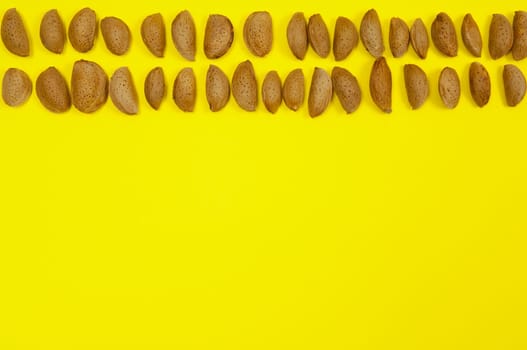 In shell raw almonds on yellow background with copy space
