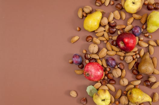 Organic autumn fruits and nuts on brown background with copy space