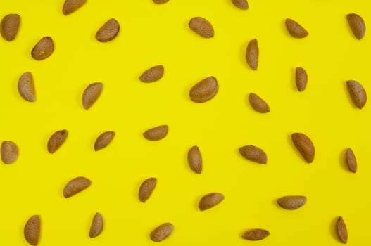 In shell raw almond on yellow background