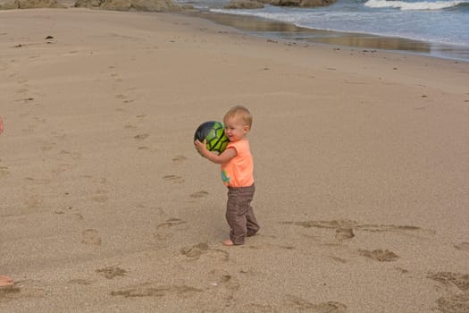 Little girl playing with a ball on the beach in Lighthouse Beach on the Oregon Coast