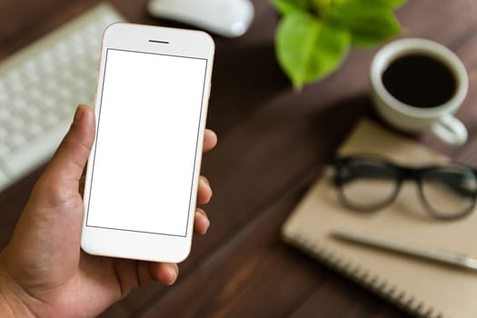 close up hand holding phone over work table, mockup phone blank screen for app screen adjustment