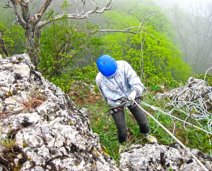 Woman climbing on steep the mountain slope. Mountains in Crimea at the sunny summer day.