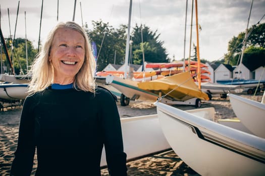 Senior woman in a boat bay wearing a wetsuit. She is looking away and is smiling.