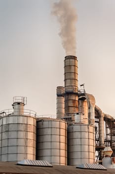 Chemical plant at sunset. Silos and smokestacks of a factory.