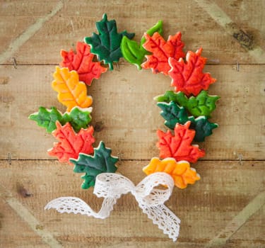 Colorful biscuits as autumn leaves on a rustic wooden background