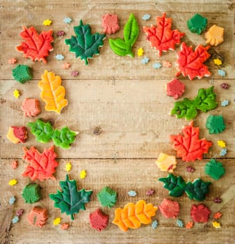 Colorful biscuits as autumn leaves on a rustic wooden background