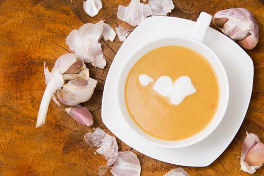 garlic cream soup in orange bowl on wooden background. rustic country style. top view