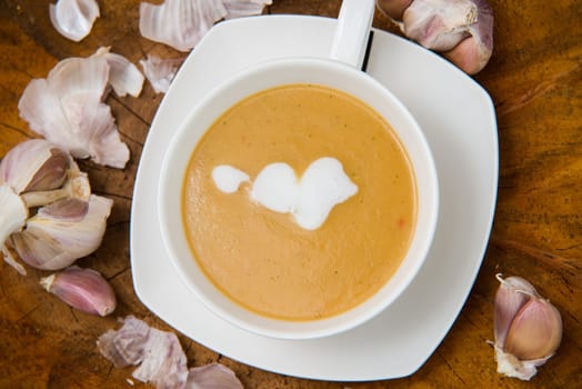 garlic cream soup in orange bowl on wooden background. rustic country style. top view