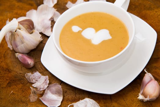 garlic cream soup in orange bowl on wooden background. rustic country style.