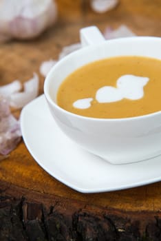 garlic cream soup in orange bowl on wooden background. rustic country style.