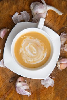 garlic cream soup in orange bowl on wooden background. rustic country style. top view