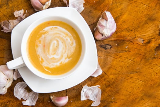 garlic cream soup in orange bowl on wooden background. rustic country style. top view