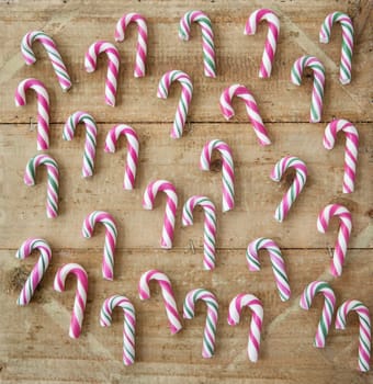 Small colorful candy canes on a rustic wooden background