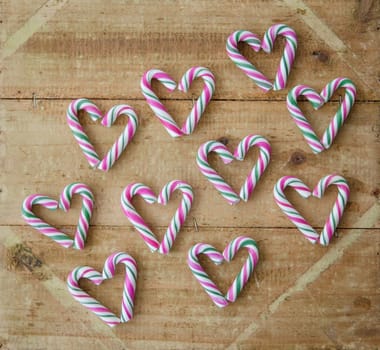 Small colorful candy canes on a rustic wooden background