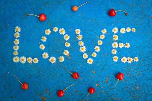 The word Love written of daisy flowers on textured blue background, top view