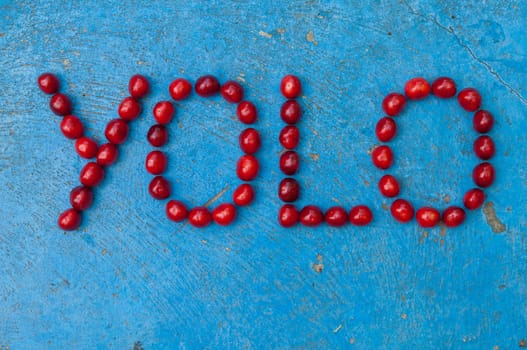 Cherries arranged to form the word YOLO on textured blue background