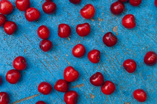 Arrangement of ripe cherries on blue textrured background, cherry pattern