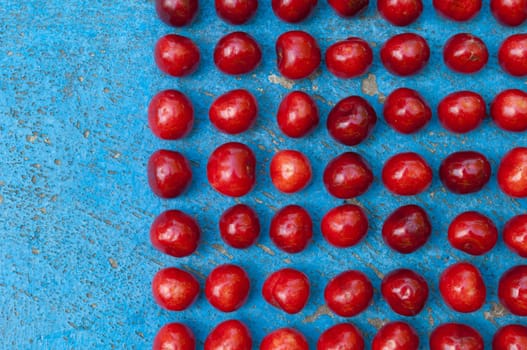 Arrangement of ripe cherries on blue textrured background, cherry pattern