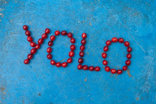 Cherries arranged to form the word YOLO on textured blue background