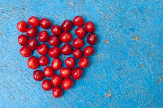 Heart shaped cherries on blue background, cherry heart, isolated