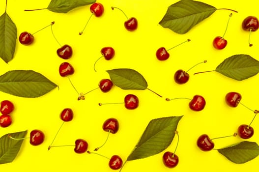 Cherry, cherries with cherry leaves on yellow background, top view