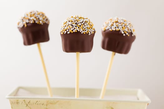 Cupcake shaped cake pops made with chocolate and tiny little pearls as topping. Very shallow depth of field