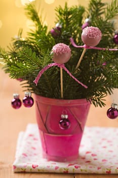 Pink cake pops with ribbon in Christmas decoration bouquet with pink baubles and some spruce