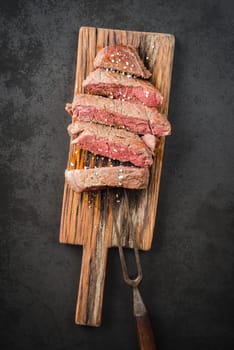 Sous vide cooked and seared fillet steak on rustic wooden board
