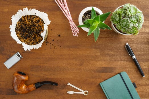 Desktop scene with pipe, succulents, tobacco, notebook and fountain pen shot from above