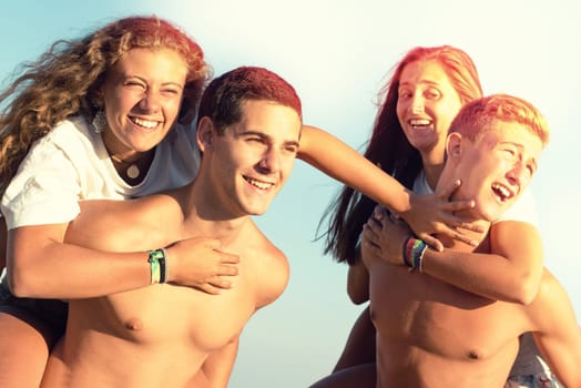 Happy teenage couples playing at the beach