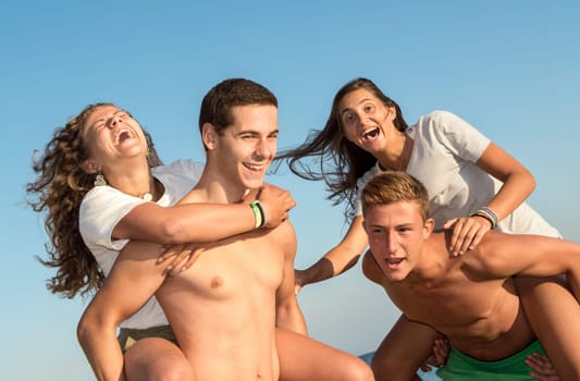 Happy teenage couples playing at the beach