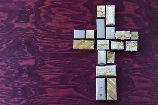 many small gifts on purple wood form a cross