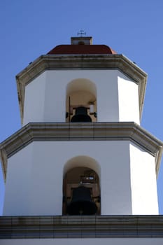 A bell tower of the Mission Basilica of San Juan Capistrano with several bells on top of each other.