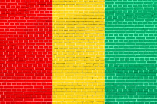Guinean national official flag. African patriotic symbol, banner, element, background. Flag of Guinea on brick wall texture background