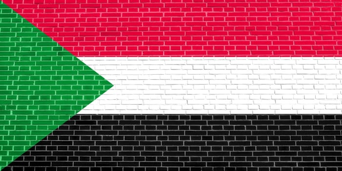 Sudanese national official flag. African patriotic symbol, banner, element, background. Flag of Sudan on brick wall texture background