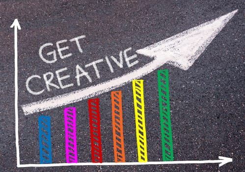 GET CREATIVE written with chalk on tarmac over colorful graph and rising arrow, business marketing and creativity concept