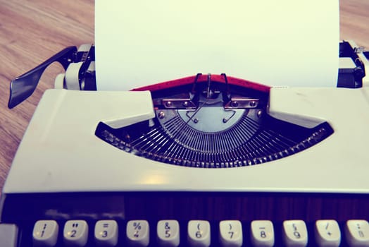 old typewriter with sheet of paper on wooden ground