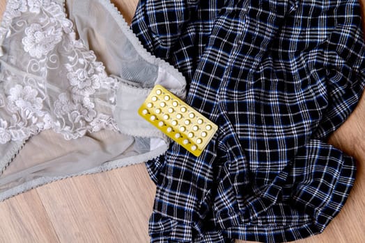 womans and mans panties with birth control pill on wooden floor