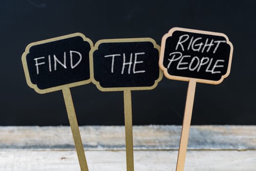 Business message FIND THE RIGHT PEOPLE written with chalk on wooden mini blackboard labels, defocused chalkboard and wood table in background