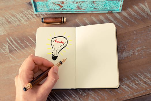 Retro effect and toned image of a woman drawing a lighting bulb with fountain pen on a notebook. KNOW-HOW symbol and concept, copy space available for text