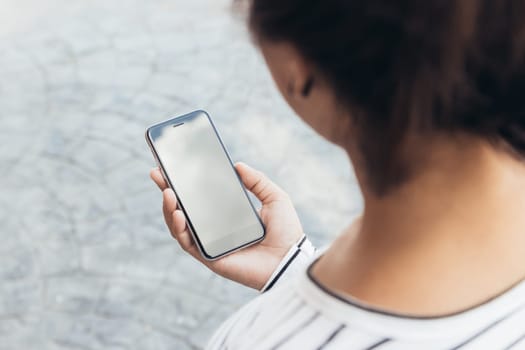 close up woman holding phone lifestyle in the city, third-person view
