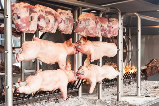 Carcasses of pork and other meat prepared on skewer. Cooking on grill and fire.