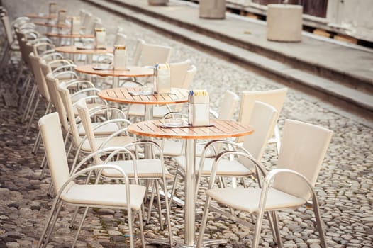 A row of small tables of a cafe on a pedestrian street