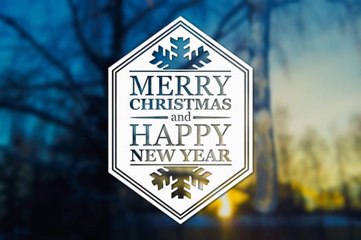 Merry Christmas and New Year greeting card on blurred tree and icicle at sunset blue colored background