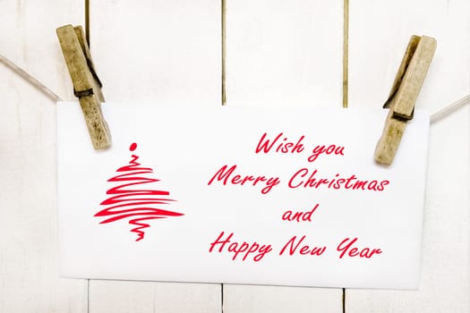 Clothespins holding on clothesline or rope holding christmas greeting card on wooden background