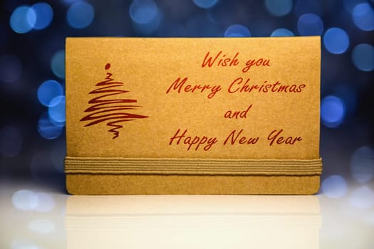 Greeting brown blank card from craft paper with reflection on Christmas lights background