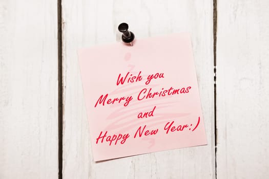 Pink Christmas greeting note paper with push black pin on wood background