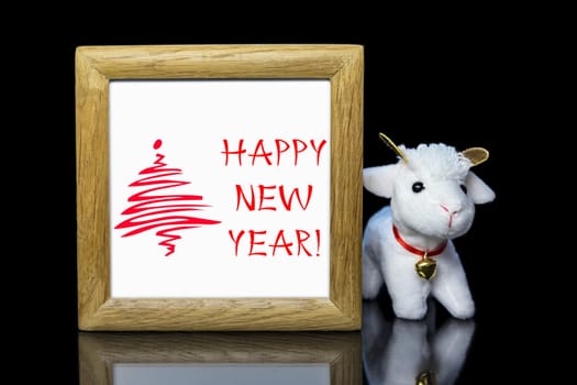 New Year greeting wooden frame with white goat or sheep toy the chinese symbol of 2015 year on black background