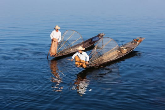 Myanmar travel attraction landmark - Traditional Burmese fishermen with fishing net at Inle lake in Myanmar famous for their distinctive one legged rowing style